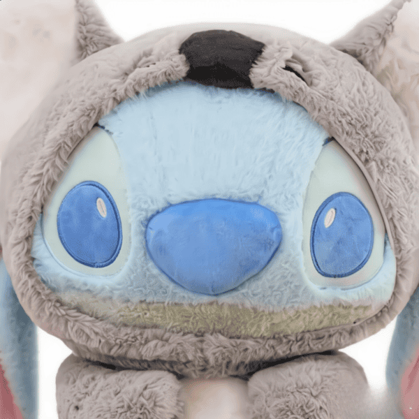 Gedetailleerde close-up van het gezicht van een blauwe pluche Stitch knuffel. Stitch heeft grote ogen, een brede glimlach en een koala-achtig uiterlijk.